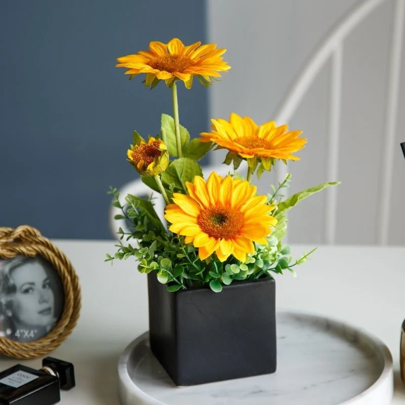 Lebensechte Blumenarrangement in dekorativem quadratischen Pflanzgefäß