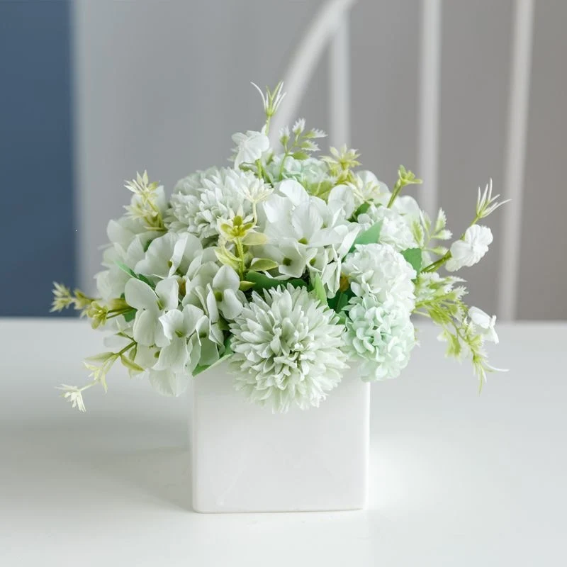 Lebensechte Blumenarrangement in dekorativem quadratischen Pflanzgefäß