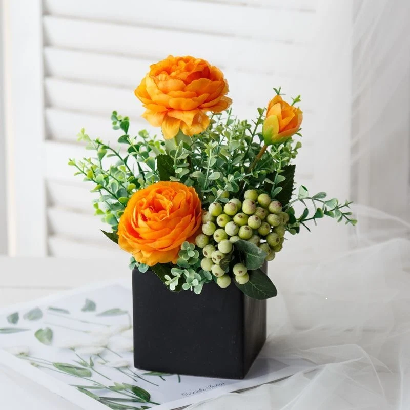 Lebensechte Blumenarrangement in dekorativem quadratischen Pflanzgefäß