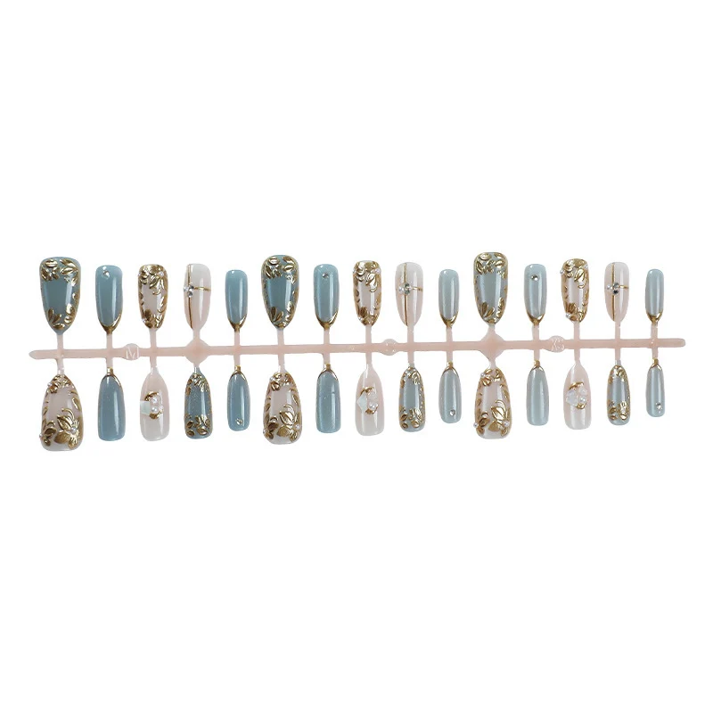 Kunstnagelset mit floralen Goldakzenten und eleganten Designs Karnz